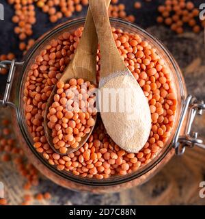 Rote Linsen und Linsenmehl in den Holzlöffeln über einer Schüssel rote Linsen. Stockfoto