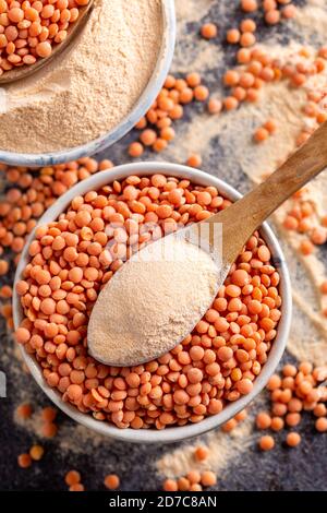 Rote Linsen und Linsenmehl in den Holzlöffeln über einer Schüssel rote Linsen. Stockfoto