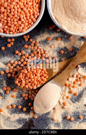 Rote Linsen und Linsenmehl in den Holzlöffeln. Hintergrund für das Essen. Stockfoto