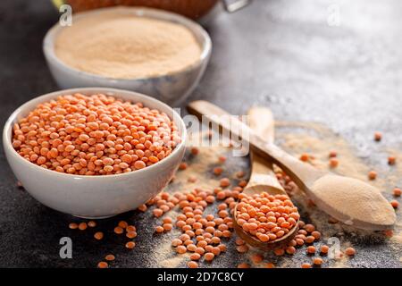 Rote Linsen und Linsenmehl in Schüssel auf dunklem Grund. Stockfoto
