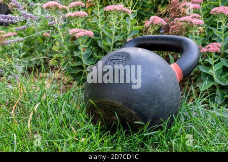 Schwere eiserne Kugelhantel auf grünem Gras in einem Hinterhof - Fitnesskonzept im Freien Stockfoto