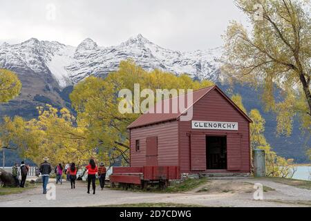 GLENORCHY, NEUSEELAND - APRIL 2018: Touristen besuchen die berühmte rote Hütte in Glenorchy am Ufer des Lake Wakatipu im Herbst mit Schnee bedeckt al Stockfoto