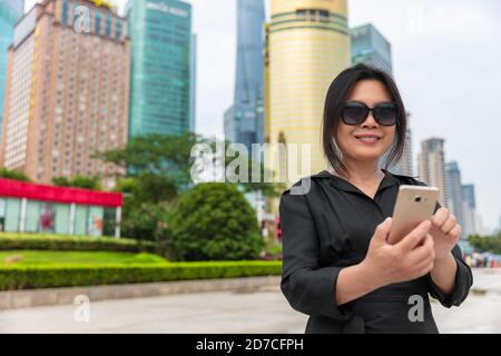 Handy Stadt Lifestyle beschäftigt Immobilien chinesische Geschäftsfrau Dame SMS mit 5g App. Asiatische Geschäftsfrau zu Fuß in Shanghai Straße, China Stockfoto