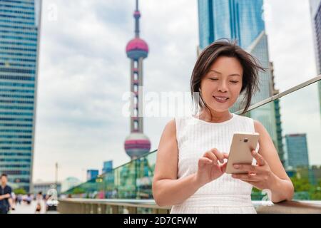 Smartphone-Geschäft mittleren Alters asiatische Frau SMS auf Handy arbeiten in Shanghai. Lächelnd reife Geschäftsfrau in der Stadt Straße, China. Echt Stockfoto