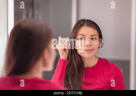 Frau setzen Make-up in der LED beleuchteten Spiegel immer bereit Morgen Beauty-Routine Anwendung Mascara Auge Make-up. Asiatische Mädchen zu Hause Lifestyle Stockfoto