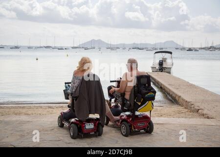 Seniorenpaar mit Mobilitätsroller mit Blick auf das Meer. Behinderter älterer Mann und Frau genießen Sommerferien. Inklusive Urlaubskonzept Stockfoto