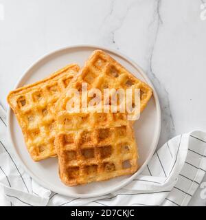 Perfekte herzhaften keto Waffeln. Zwei Zutaten chaffles auf die Platte über der weißen Marmor Hintergrund. Eier und Parmesan low carb Waffeln. Top View oder flach. Kopieren Sie Platz für Text oder Design. Stockfoto