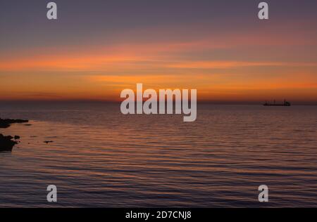 Heller Sonnenuntergang Himmel über dem Meer. Wunderbarer Himmel nach Sonnenuntergang in Orangentönen. Der natürliche Hintergrund. Lila Farbton des Meeres und des Himmels. Zusammenfassung Stockfoto