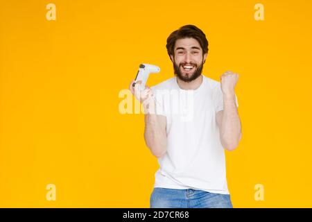 Fröhlicher junger Mann in beiläufigen weißen T-Shirt posiert isoliert auf gelb orange Hintergrund, Studio-Porträt. Menschen Lifestyle-Konzept. Erstellen Sie einen Mock-up-Kopierbereich Stockfoto