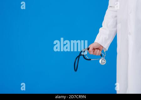 Arzt mit Stethoskop in der Hand, blauer Hintergrund aus der Nähe Stockfoto
