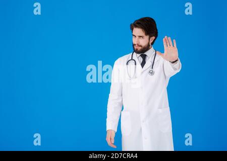 Porträt eines seriösen Arztes in professionellen medizinischen weißen Mantel zeigt Ablehnung Geste von Anschlag Handfläche Zeichen. DOC man isoliert auf blauem Hintergrund. Stockfoto