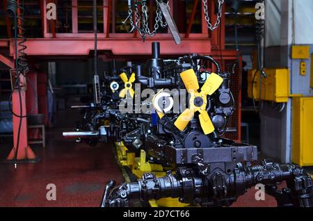 Neue Motoren auf der Montagelinie der industriellen Fabrik. Traktorenfertigung. Installation von Teilen auf landwirtschaftlichen Maschinen Fabrik. Geringe Rauheit Stockfoto
