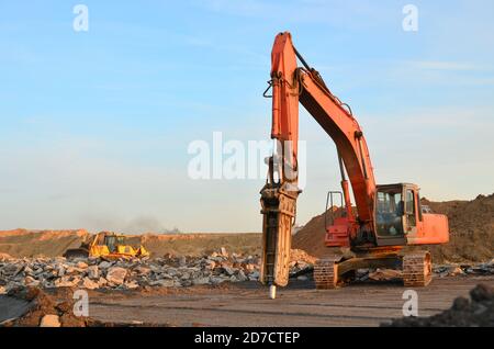 Hydraulikhammer für die Zerstörung von Beton und Hartgestein auf der Baustelle. Bagger auf Sonnenuntergang Hintergrund. Presslufthammer mit Stockfoto