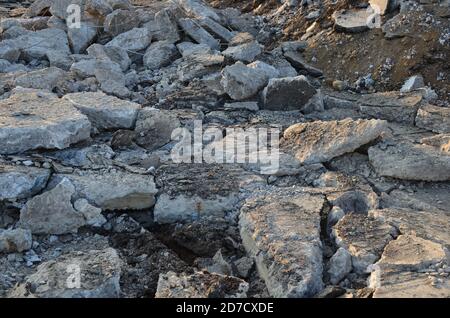 Zerbrochene Asphaltstücke auf einer Baustelle. Recycling und Wiederverwendung zerkleinerten Betonschutt, Asphalt, Baumaterial, Blöcke. Zerkleinert сoncrete Bac Stockfoto