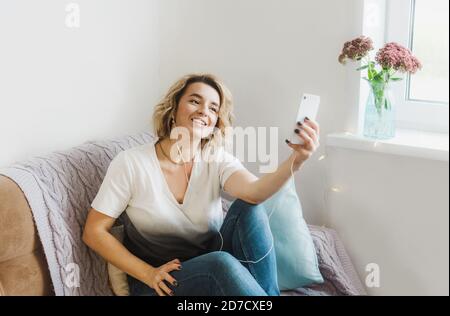 Ein junges Mädchen Blogger kommuniziert mit ihren Abonnenten sitzen an Zuhause auf der Couch in gemütlicher Atmosphäre Stockfoto