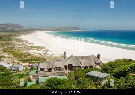 Langer Strand, mit gekröntem Eagle Resort vor, Chapmans Peak, Kapstadt, Südafrika. Stockfoto