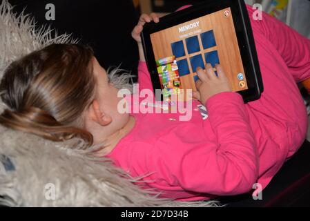 Kleines Mädchen in Pyjamas spielen auf ihrem digitalen Tablet Stockfoto