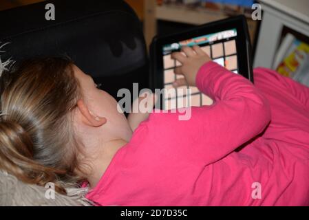 Kleines Mädchen in Pyjamas spielen auf ihrem digitalen Tablet Stockfoto