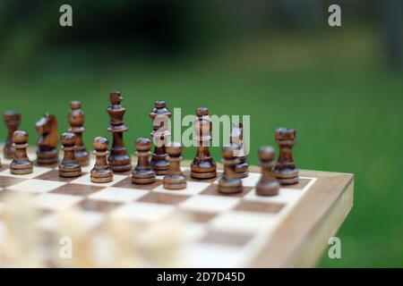 Schachfiguren auf dem Schachbrett, außen, niedrige Schärfentiefe, konzentrieren sich auf schwarze Stücke Stockfoto