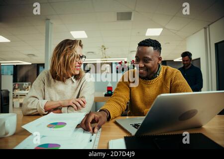 Junge Frau diskutiert Dokumente mit Geschäftsmann Recherche auf Laptop arbeiten Im Foyer des Büros zwischen den Sitzungen Stockfoto