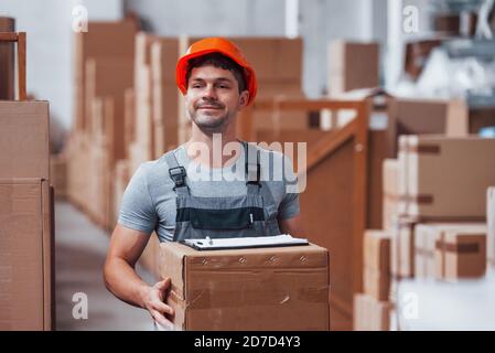 Arbeiter in orange hart hatte ist im Lager mit Box in den Händen Stockfoto