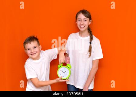 Lachende junge kaukasier zwei Freunde Kerl und Mädchen in weißen leeren leeren Design-T-Shirts posiert auf orangen Studio Wand. Stockfoto