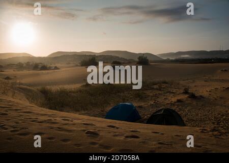 Blick auf zwei Zelten Camping in der Mitte von riesigen Sand die Dünen, am frühen Morgen mit dem Nebel aufklären Stockfoto