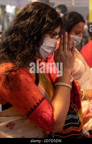 Während des Durga Puja-Festivals in Dhaka betet ein Anhänger mit Gesichtsbehaarung an ein Idol der Göttin Durga.Gesundheitsbeamte haben vor dem Potenzial gewarnt, dass sich das Coronavirus während der kommenden religiösen Festsaison ausbreiten kann, die von riesigen Versammlungen in Tempeln gekennzeichnet ist. Stockfoto