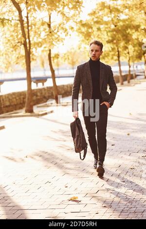 Der junge Mann in formeller Kleidung spaziert im Herbstpark An sonnigen Tagen Stockfoto