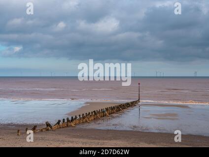 Der Strand bei Withernsea East Yorkshire mit hölzernen Seegrille und Offshore-Windpark in der Ferne. Stockfoto