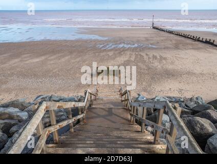 Treppen führen hinunter zu einem Sandstrand mit der Flut unsere und das Meer in der Ferne. Stockfoto