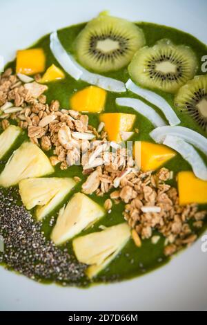 Smoothie Schüssel mit Kiwi, Kokosnuss, Mango, Ananas, Müsli und Chiasamen mit grünem Joghurt Stockfoto