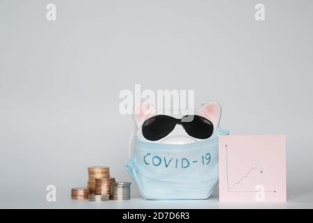 Der Zusammenbruch der Finanzmärkte und die Gefahr für finanzielle Ersparnisse aufgrund eines Pandemie-Virus.Masked Sparschwein Stockfoto