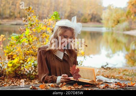 Porträt einer jungen Frau im Retro-Kleid Lesen eines Buches Im Herbst Park Stockfoto