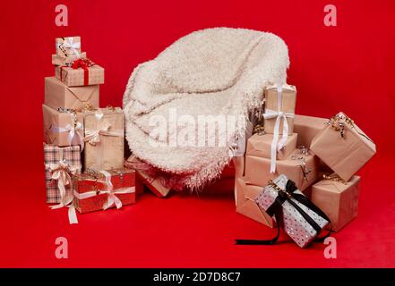 Sessel mit Kariert und Geschenke auf rotem Hintergrund. Stockfoto