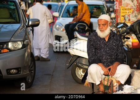 Mumbai, Indien - 22. März 2019: Unbekannter alter muslimischer Mann sitzt auf einem kleinen Stuhl am Straßenrand an der Bergstraße, Bandra in Mumbai. Stockfoto
