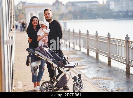 Fröhliche Familie mit Kinderwagen haben einen Spaziergang zusammen mit ihren Kind im Park Stockfoto