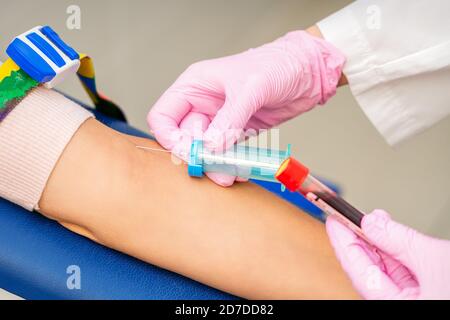 Krankenschwester auf rosa Handschuhe nimmt Blutprobe aus der Vene Weibliche Patientin im medizinischen Labor Stockfoto