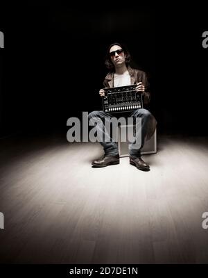 Hip-Hop-Musikerportrait mit Beat-Maschine und dunklem Studiobeleuchtung. Stockfoto