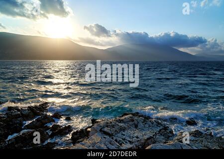 Schöne Meereslandschaft mit Bergen im Hintergrund und Sonne Strahlen ragen durch die Wolken Stockfoto