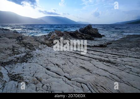 Schöne Meereslandschaft mit Bergen im Hintergrund und Sonne Strahlen ragen durch die Wolken Stockfoto