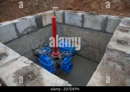 Schieber in der Schiebergrube der Erdleitungsnetze. Verlegung der Wasserleitung auf der Baustelle. Wasserleitung, Rohre in Graben Stockfoto