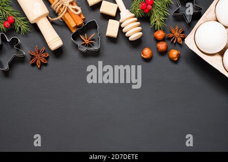 Formen und Zutaten für die Herstellung von weihnachtskeksen auf schwarzem Hintergrund mit Kopierplatz. Stockfoto