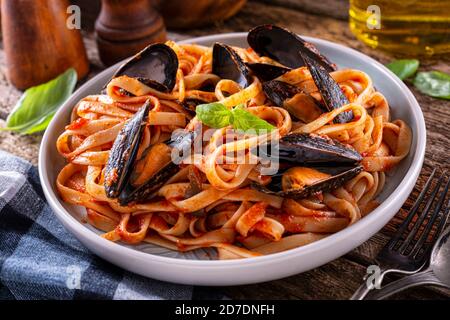 Ein Teller mit leckeren Muscheln mit Marinara Tomatensauce und Fettuccine. Stockfoto