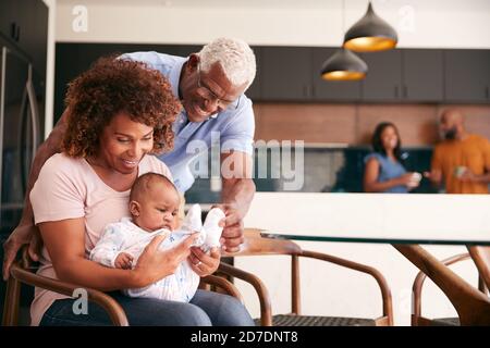 Großeltern Kuddeln Baby Enkelin Zu Hause Mit Eltern Im Hintergrund Stockfoto