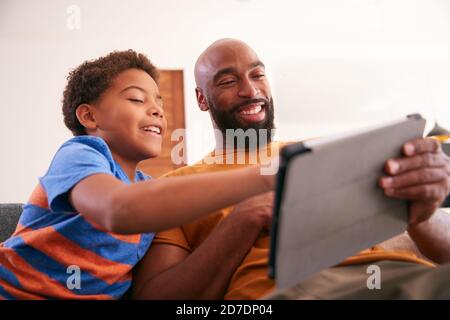 Afroamerikanische Familie Zu Hause Mit Vater Und Sohn Sitzen Auf Sofa Zu Hause Mit Digitalem Tablet Stockfoto