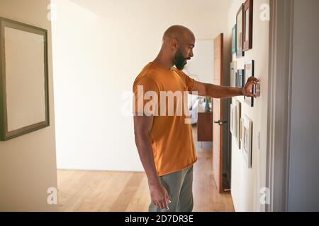 Mann, Der Das Digitale Zentrale Heizthermostat Zu Hause Justiert Stockfoto