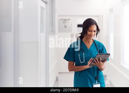 Weibliche Doctor Trägt Scrubs Im Krankenhaus Korridor Mit Digital Tablet Stockfoto