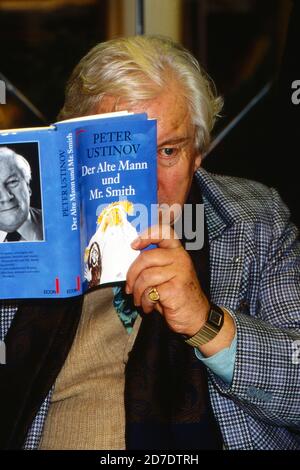 Sir Peter Ustinov versteckt sich bei einer Lesung hinter seinem Buch 'der alte Mann und Mr Smith', Deutschland 1991. Stockfoto