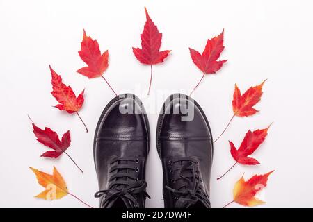 Schwarze Lederstiefel und rote Blätter auf weißem Hintergrund. Herbstangebot. Draufsicht - Bild Stockfoto